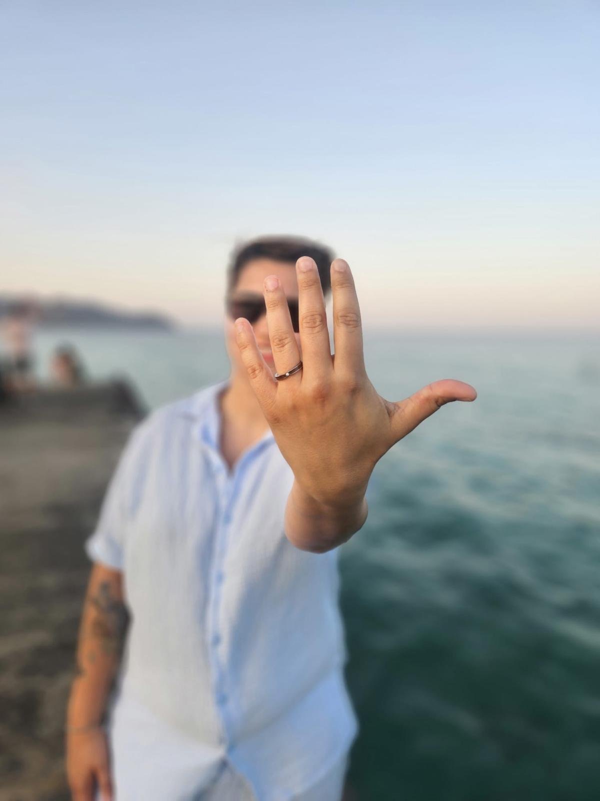 Hand mit Verlobungsring vor dem Meer