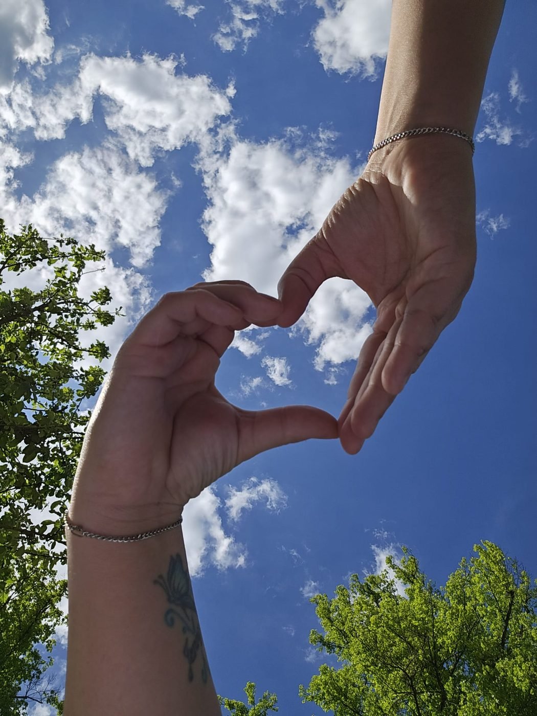Zwei Hände formen ein Herz vor dem Himmel